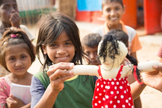 Rohingya children playing with a doll at a refugee camp in Bangladesh.