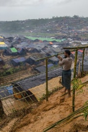 Un uomo costruisce un rifugio in legno per la propria famiglia ai margini del campo profughi a Cox’s Bazar.