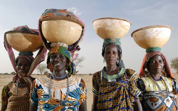 Quatre femmes portant sur leur tête des paniers remplis de céréales.