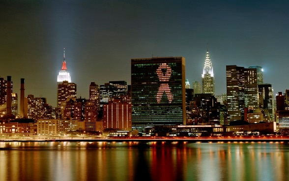 Illuminazione gigante su un grattacielo che raffigura il nastro rosso della lotta all’AIDS.