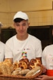 Three baker apprentices showing the bread they have made.