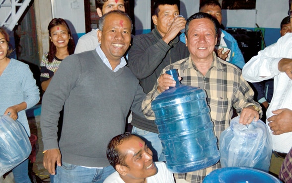 A group of around ten people carry bottles of water in Nepal. 