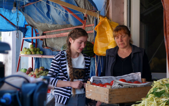 L’image montre une vendeuse du marché de Senaki qui pèse les tomates que Medea et son père ont amené.