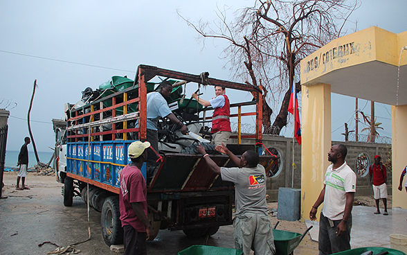 Un gruppo di uomini scarica un camion di carriole e attrezzi vari.