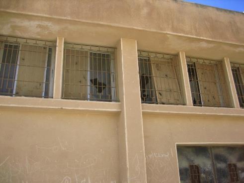 Schulgebäude mit beschädigter Fassade und zerbrochenen Fensterscheiben 