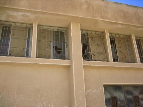 Damaged façade of a school with broken windows 