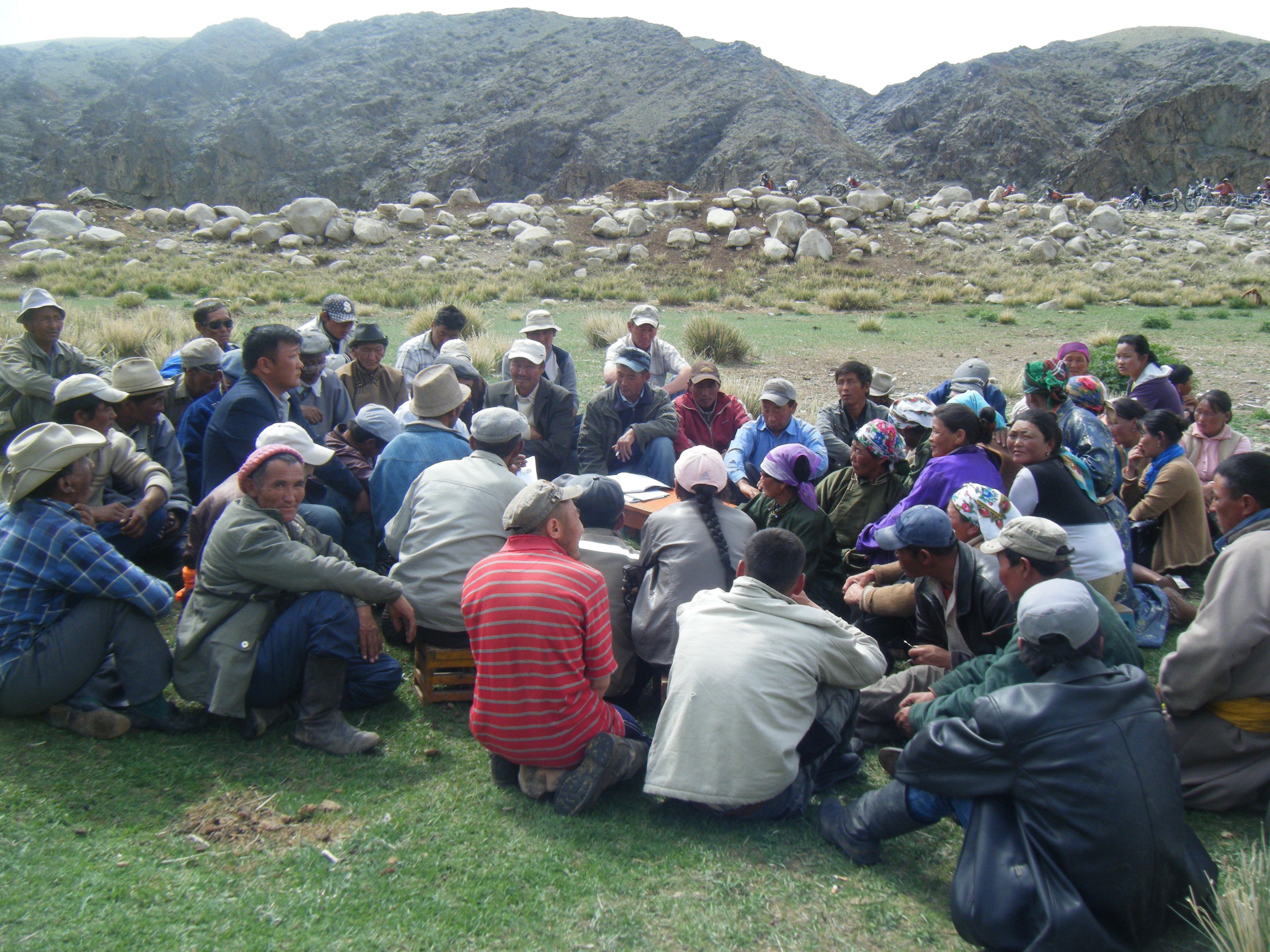 Grupo de pastores y pastoras sentados en la hierba, en pleno debate.