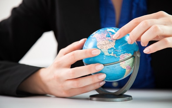 Deux mains tiennent un petit globe terrestre.