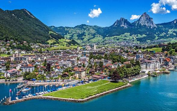 Vista della città di Brunnen dall'alto con la Auslandschweizerplatz ben visibile, il lago e le montagne sullo sfondo.