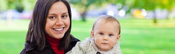 Eine junge Frau trägt ein Kind auf den Armen