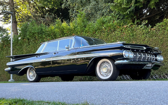 A black, vintage car parked on the side of a road.