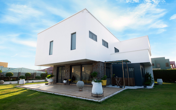 Une maison blanche moderne, agrémentée d’une terrasse et d’un jardin.