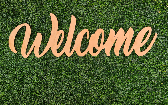 An orange ‘Welcome’ sign on a green lawn.