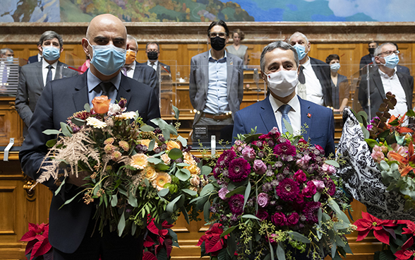 Close-up of Ignazio Cassis and Alain Berset in Parliament during the election. They carry bouquets of flowers.