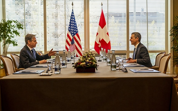 President Cassis and Foreign Minister Blinken sit across from each other at a table and talk.