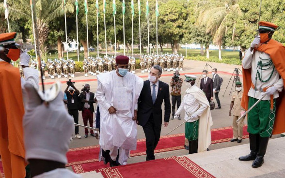 Bundespräsident Cassis und der nigrische Präsident Bazoum schreiten eine Treppe hinauf.