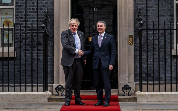 Federal Councillor Ignazio Cassis and Prime Minister Boris Johnson stand on a red carpet in front of the entrance to the Prime Minister's residence at 10 Downing Street and shake hands.