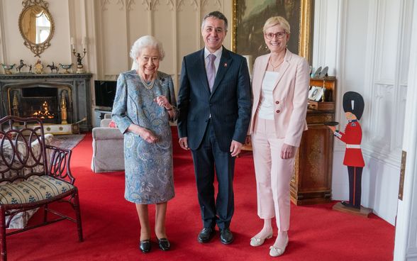 Le président de la Confédération Cassis pose entre son épouse Paola Rodoni Cassis et la reine Elizabeth II.