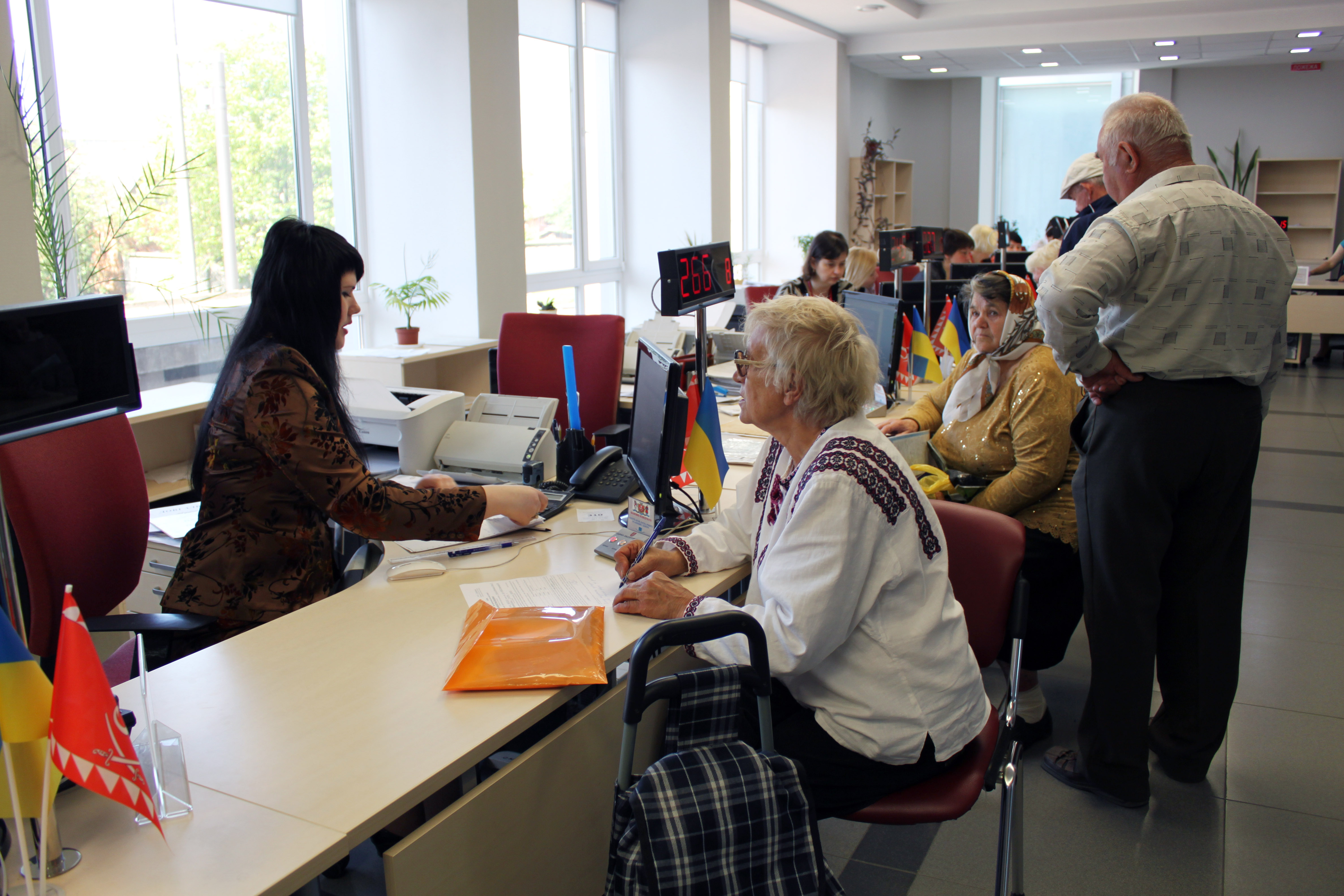 Su una fila di postazioni di lavoro, impiegati parlano con varie persone.