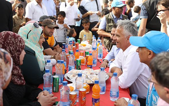 Didier Burkhalter e alcuni abitanti del campo di Azraq bevono seduti a un tavolo.