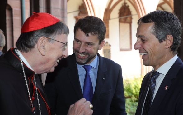 Alt-Text: Federal Councillor Ignazio Cassis speaks with Cardinal Curt Koch and Rev. Gottfried Locher, President of the Federation of Swiss Protestant Churches. 