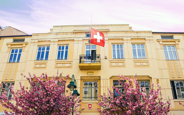 L’edificio dell’Ambasciata di Svizzera, con la bandiera rossocrociata e due alberi in primo piano.