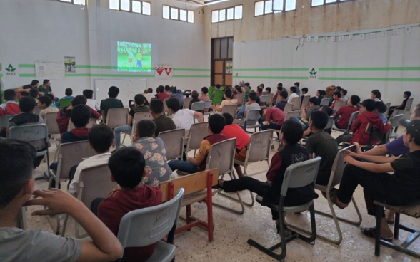 Syrian children watch a cartoon film in a hall.