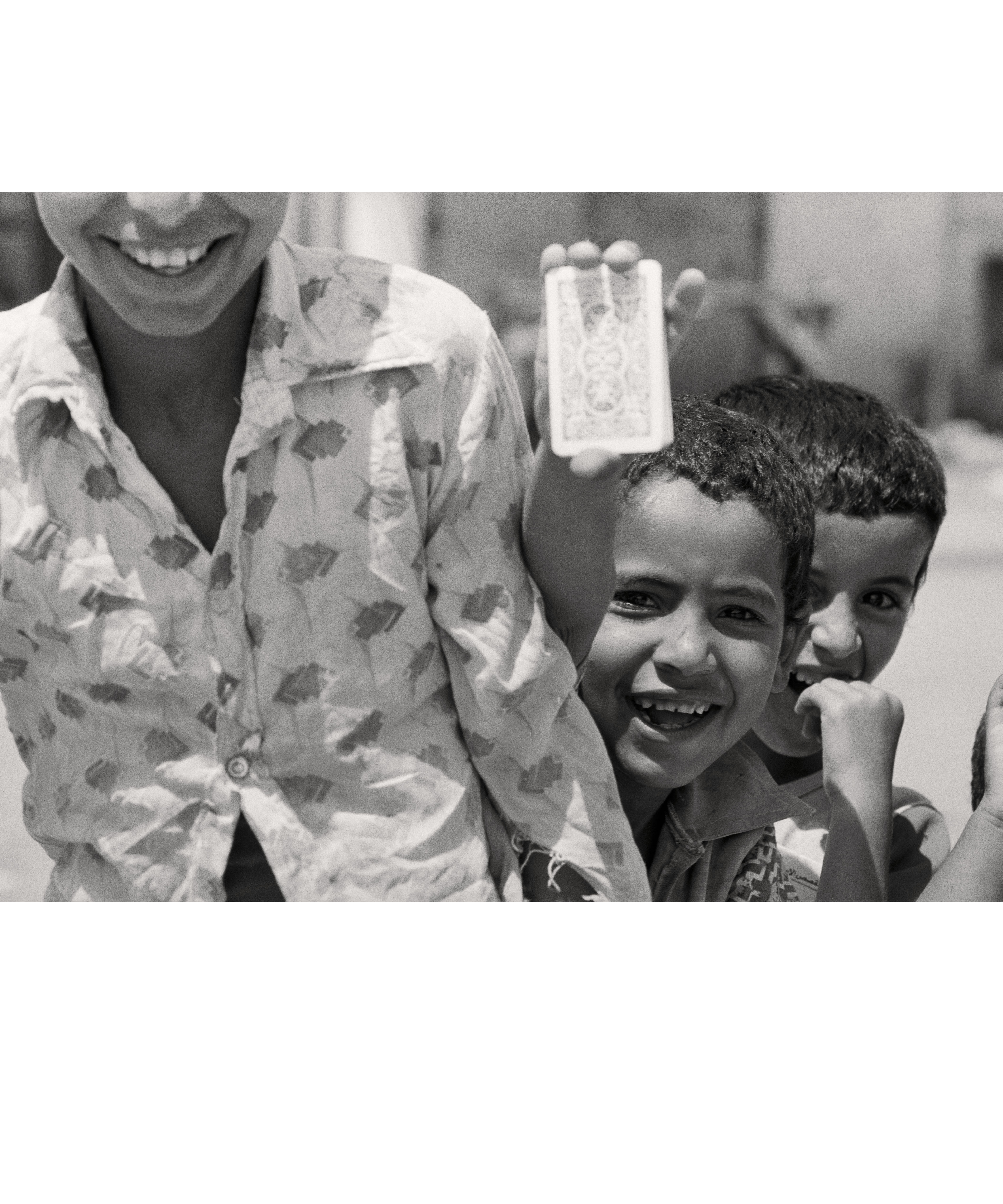 Smiling Palestinian refugee children holding up a pack of cards 