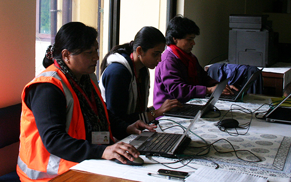 Lokale Mitarbeitende der Schweizer Botschaft in Nepal sitzen an einem Tisch und arbeiten.