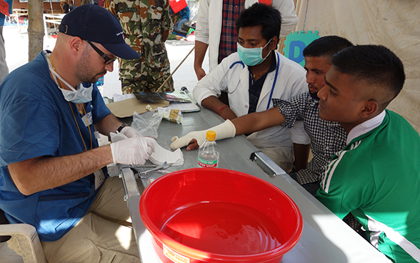 A member of the Swiss medical team bandages the injured hand of an earthquake victim in Nepal.