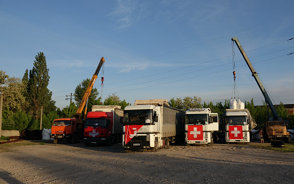 Des grues chargent le matériel dans les camions du convoi.