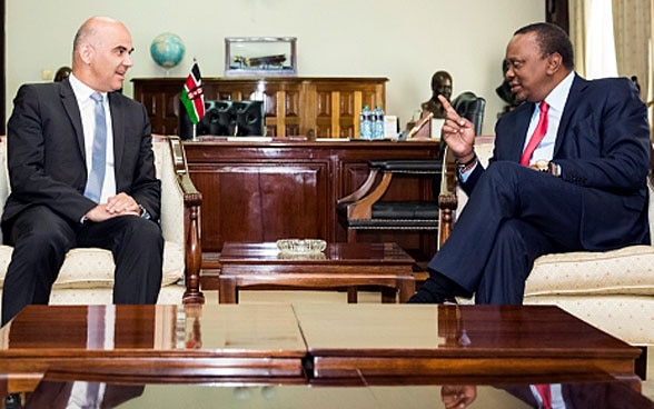 Le président de la Confédération Berset et le Président kényan Kenyatta sont assis à une table en bois et discutent. 