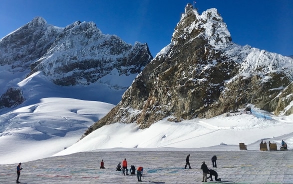 Sur le glacier d'Aletsch, des gens assemblent la carte postale. A l'arrière-plan, vous pouvez voir le Jungfraujoch. 