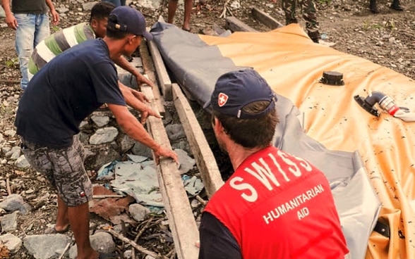 A member of the Swiss Humanitarian Aid Unit helps the local population rebuild water infrastructure after a catastrophe.