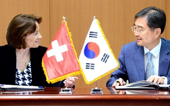 Pascale Baeriswyl et Cho Hyun s'assoient à une table en bois et parlent.