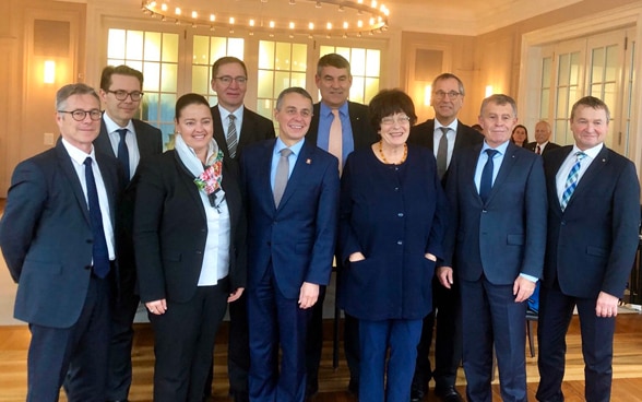 Bundesrat Ignazio Cassis mit den Regierungschefinnen und -chefs der Internationalen Bodensee-Konferenzin einem hell beleuchteten Raum. 