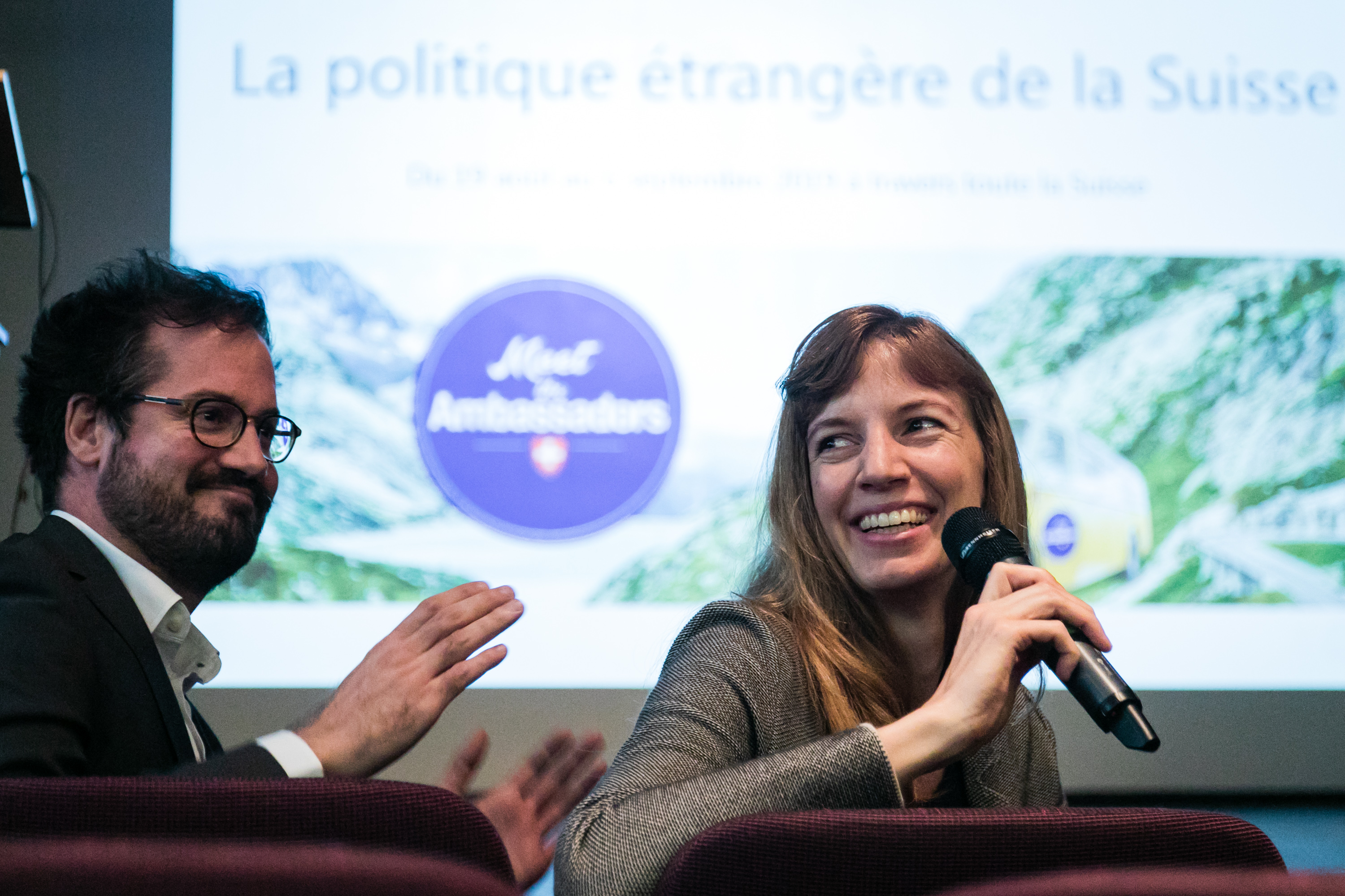 Une diplomate est assise au premier rang et répond au public avec le micro à la main