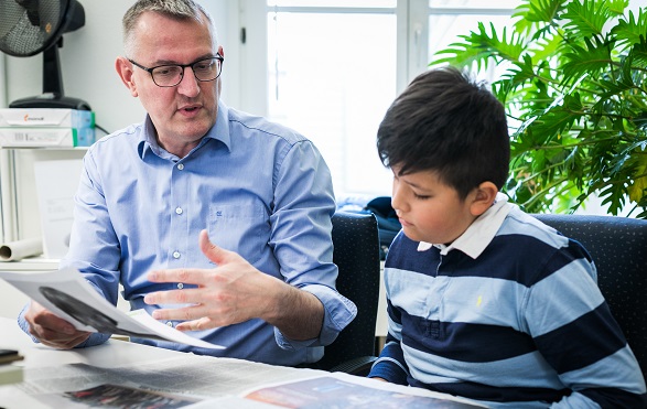 A boy is watching a man at work.