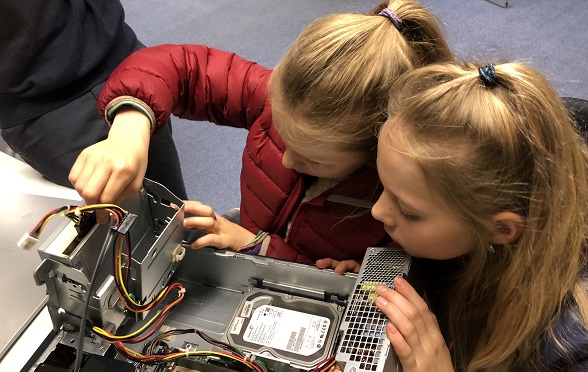 Zwei Mädchen hantieren mit dem Innern eines Computers. 