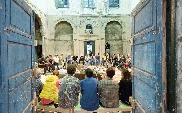 Un gruppo di giovani siede in cerchio nel cortile interno di un edificio in occasione del festival Dream City di Tunisi. 