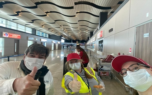Pollici in su, berretti e maschere svizzere sono di rigore per una fotografia all'aeroporto di Dakar prima del volo per la Svizzera.
