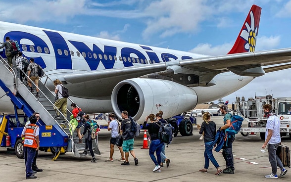 Un avion, devant lequel se trouve l'escalier de service, par lequel un certain nombre de passagers embarquent.