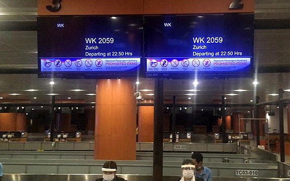 Zwei Bildschirme in der Abflughalle des Flughafens von Yangon zeigt den Flug nach Zürich an. 