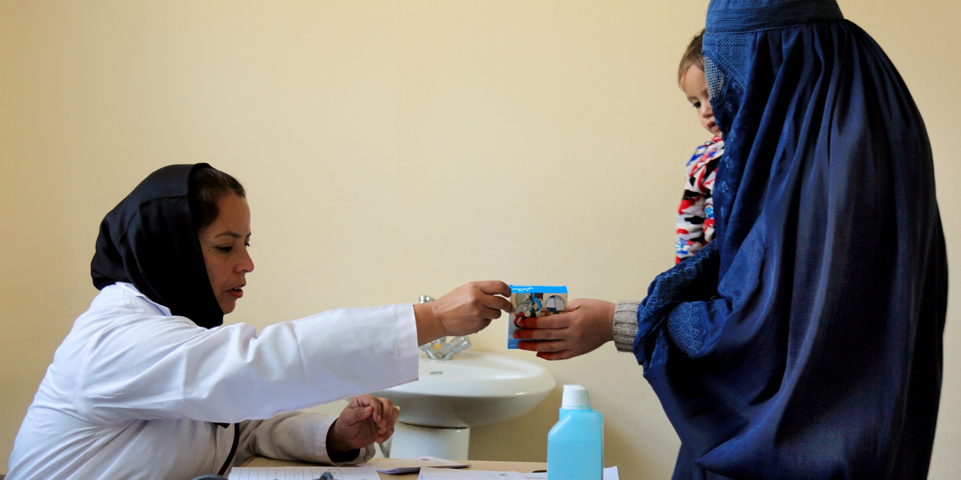 Une mère avec son enfant dans les bras reçoit un médicament d'un employé de l'hôpital à Kaboul/Afghanistan. 