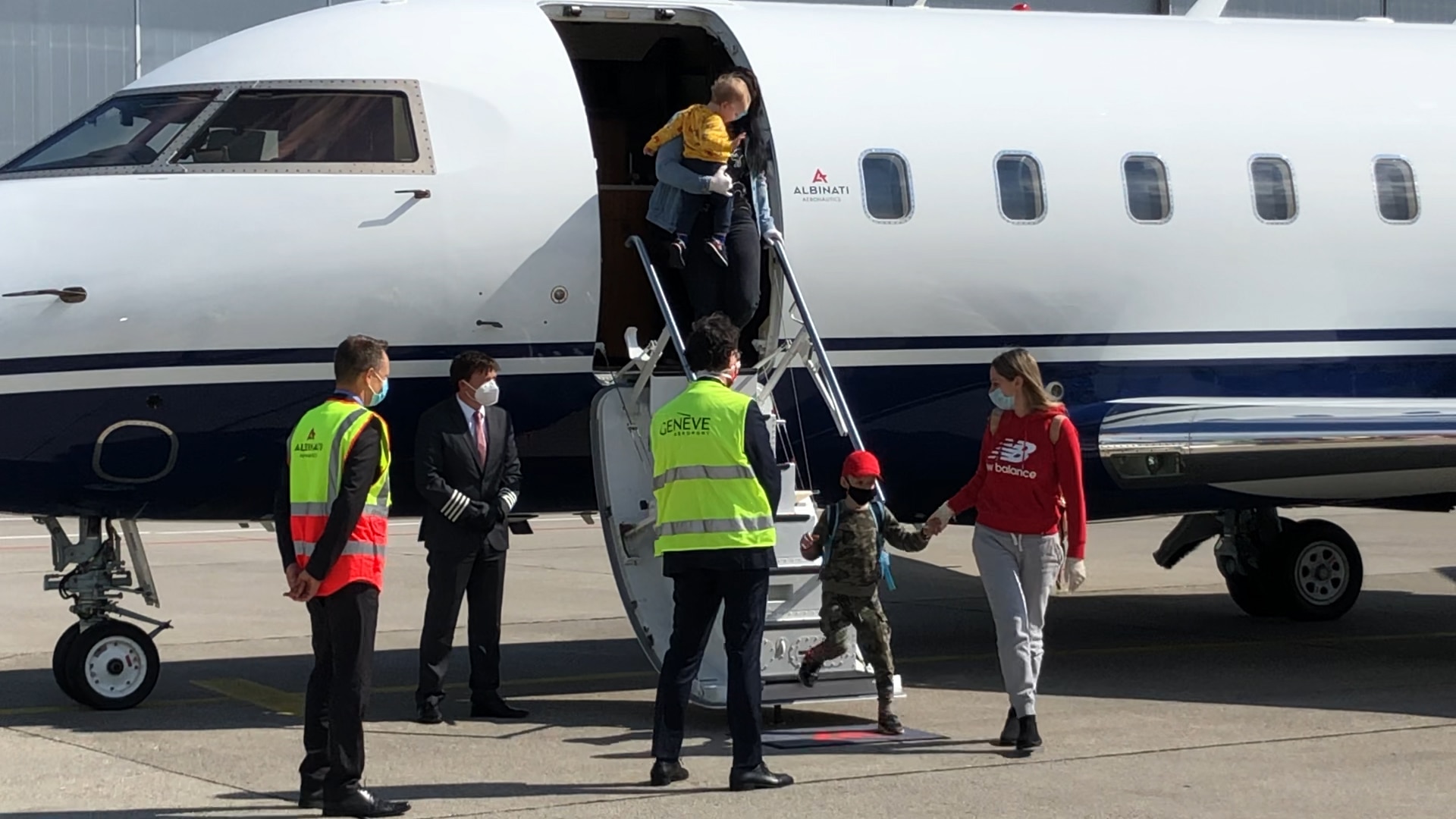 At Geneva airport, adults and children board a bus from the plane.