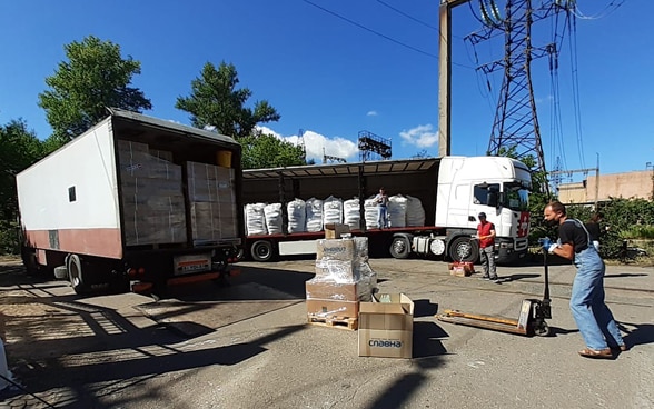  Des logisticiens de l'aide humanitaire suisse chargent des fournitures de secours dans un camion.