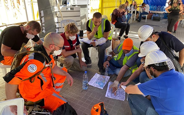 Des experts du Corps suisse d'aide humanitaire discutent d'une carte de la région.