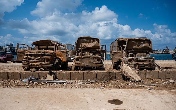 Three destroyed vehicles stand in the port of Beirut.