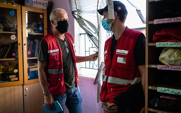 Deux experts du Corps suisse d'aide humanitaire s'entretiennent dans une salle de classe détruite.