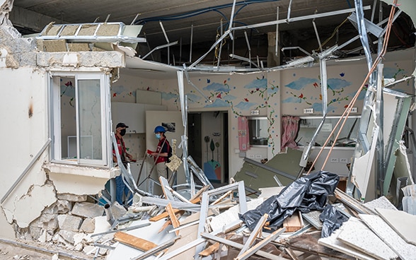 Two experts from the Swiss Humanitarian Aid Unit are standing in the destroyed hospital in the Karantina district.
